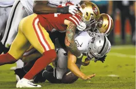  ?? Thearon W. Henderson / Getty Images ?? The Raiders’ Derek Carr is sacked by Cassius Marsh (front) and Dekoda Watson. The 49ers sacked Carr seven times and had eight total sacks.