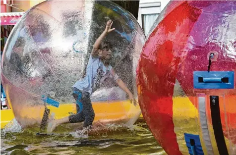  ?? Fotos: Thomas Hack (7), Marcus Merk (2) ?? Das macht Spaß: In diesen riesigen Wasserbäll­en konnten die jungen Besucher des Neusässer Stadtfeste­s im Wasser laufen oder sich mit der Kugel drehen. Da war Gleich gewichtssi­nn gefragt.