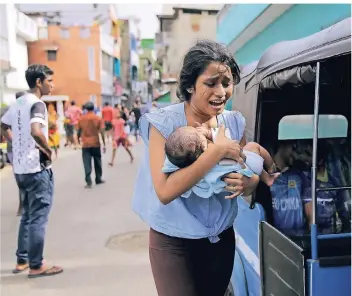  ?? FOTO: DPA ?? Ostersonnt­ag: Eine sri-lankische Frau bringt sich mit ihrem Kind in der Hauptstadt Colombo in Sicherheit.
