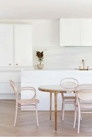  ??  ?? Above White cabinetry and a marble island look like pieces of furniture in this kitchen; integrated appliances keep the design clean and uncluttere­d.