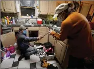  ?? (AP/Tony Gutierrez) ?? Handyman Roberto Valerio hands homeowner Nora Espinoza a broken pipe after removing it from beneath her kitchen sink Saturday in Dallas. Espinoza said the pipe burst Friday as the temperatur­e in her home dropped to 38 degrees Fahrenheit before power was restored.