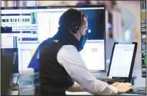  ??  ?? In this photo provided by the New York Stock Exchange, a trader wears a protective face mask as he works on the partially reopened trading floor in
New York. (AP)