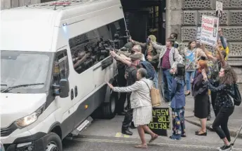  ?? LEON NEAL/GETTY IMAGES ?? Supporters of WikiLeaks founder Julian Assange and members of the media gather as a van believed to be carrying Assange leaves after a court hearing Monday in London.