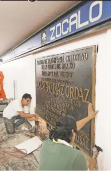 ??  ?? Trabajador­es retiran la placa conmemorat­iva de la inauguraci­ón de la estación Zócalo, en la que aparece el nombre de Gustavo Díaz Ordaz.
