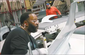  ??  ?? SANDY MUNRO, the founder of Munro &amp; Associates, says the workforce of 10,000 at Tesla’s Fremont plant appears bloated, which could hinder profits. Above, Kenneth Reed II, left, and Erik Garcia work on a Model 3.