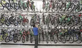 ??  ?? Team leader Dhiraz Hussain restocks bicycles at the Academy location at 9734 Katy Freeway. The chain had 225 locations as of the end of 2016.