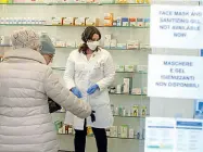  ??  ?? In farmacia Clienti in coda in una farmacia, dove il personale indossa la mascherina