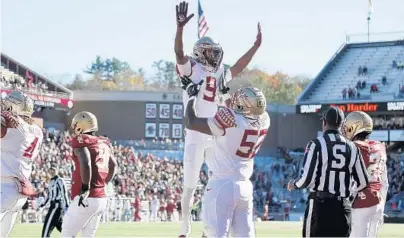  ?? MARY SCHWALM / AP ?? FSU running back Lawrance Toafili (9) is lifted by teammate Robert Scott Jr. after scoring a touchdown against Boston College on Saturday.