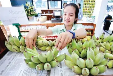  ?? HONG MENEA ?? A store attendant arranges organic bananas on a shelf at the Khmer Cooperativ­e Organic shop in Phnom Penh.