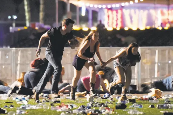  ?? David Becker / Getty Images ?? People run as others lie on the ground to try to escape the gunfire that killed at least 59 and wounded 527 others at a country music festival Sunday in Las Vegas.