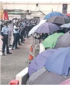  ?? FOTO: DPA ?? Polizisten stehen Wache, Demonstran­ten schützen sich mit Regenschir­men.