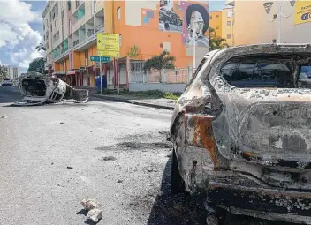  ?? Elodie Soupama / Associated Press ?? Charred cars litter a street in Le Gosier on the French Caribbean island of Guadeloupe, where protests erupted over France’s mandatory vaccinatio­ns for health care workers and a COVID-19 health pass.