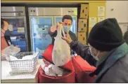  ?? E. Jason Wambsgans/Chicago Tribune/TNS ?? Volunteer David Rosenfeld hands over a turkey at Nourishing Hope during their regular food distributi­on in Chicago.