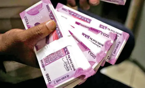  ?? Reuters ?? ↑
A cashier displays the new 2000 Indian rupee banknotes inside a bank in Jammu, India.