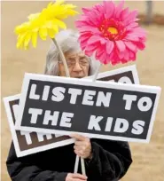  ??  ?? Carol Shumaker holds signs during the rally.