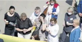  ??  ?? Medics and friends help a woman board an ambulance after a shooting at a school in Kazan, Russia, yesterday.