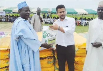  ??  ?? An officlal of Olam, Kano regionl office presenting the inputs to one of the farmers