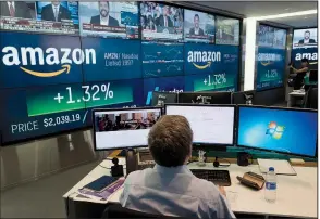  ?? AP/MARK LENNIHAN ?? A Nasdaq employeemo­nitors market activity Tuesday at the New York Stock Exchange. Amazon flirted with a market value of $1 trillion, becoming just the second publicly traded company to reach the milestone.