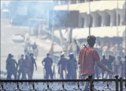  ?? Hadi Mizban The Associated Press ?? Iraqi riot police fire tear gas to disperse anti-government protesters gathering on a bridge in central Baghdad on Saturday.