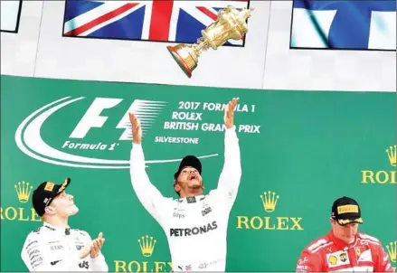  ?? BEN STANSALL/AFP ?? Mercedes driver Lewis Hamilton (centre) celebrates on the podium next to second placed teammate Valtteri Bottas (left) and third placed Ferrari driver Kimi Raikkonen after winning the British Grand Prix yesterday.