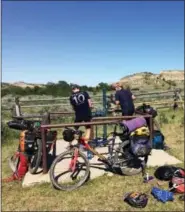  ?? CAREY J. WILLIAMS — THE ASSOCIATED PRESS ?? Drew Redman pumping water for Ryan Johnson’s various containers. Each campsite along the Maah Daah Hey Trail in western North Dakota, located at least 18 miles apart, had hand-pumped drinking water for hikers, horseback riders or mountain bikers.