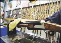  ?? CP PHOTO ?? An Ottawa hunting store salesperso­n wipes a shotgun on Tuesday, May 16, 2006. Gun control could wind up being a defining issue in next year’s federal election. Eighteen months ahead of the vote, both the governing party and the official Opposition are...