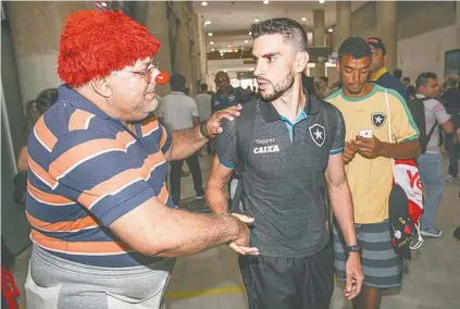  ??  ?? Pimpão cumpriment­a um torcedor que foi ao aeroporto vestido de palhaço