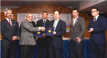  ??  ?? Ong (fourth right) witnesses the exchange of MOA documents between Rasid (third left) and Lau (third right) while (from left) No’man, Wong, Goh (far right) and others look on.