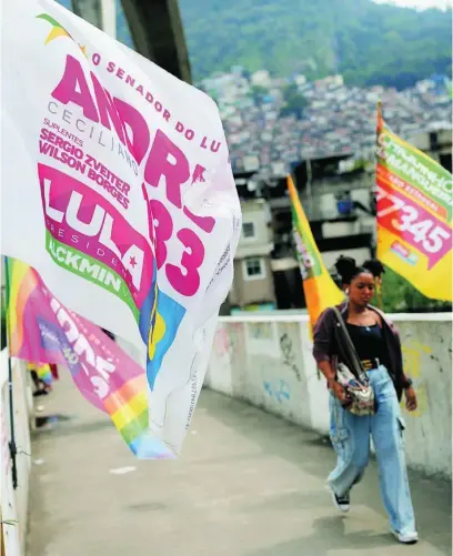  ?? AP ?? Una joven pasea por la favela Rocinha de Rio de Janeiro junto a una bandera a favor de Lula