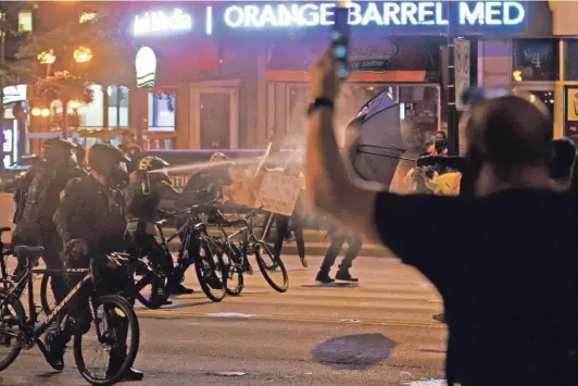  ?? JOSHUA A. BICKEL/COLUMBUS DISPATCH ?? Columbus police officers use pepper spray to disperse protesters following the death of George Floyd last May.