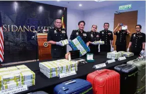  ??  ?? Bundles of money: Azam (second from left) and his officers showing the seized money during the press conference in Putrajaya.