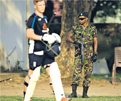  ??  ?? Under guard: A soldier keeps a watchful eye as the England sqaud practise in the nets in Colombo yesterday