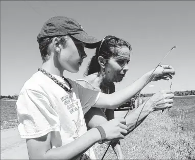  ??  ?? Brigid O’Donoghue helps Logan Neitman of Franklin during a fishing outing on a cranberry farm near Pittsville.