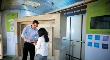  ??  ?? NWMOs Chief Engineer, Chris Boyle, explains the properties of the Used Fuel Transporta­tion Package to a community member. (This photo was taken preCOVID-19 pandemic before public health measures were in place).