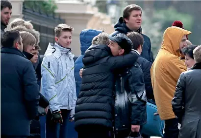  ?? AFP ?? people hug as they carry luggage leaving the russian embassy in London on Tuesday .—