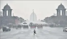  ?? PTI ?? A man runs for cover near Vijay Chowk as heavy rain lashed the city on Saturday. n