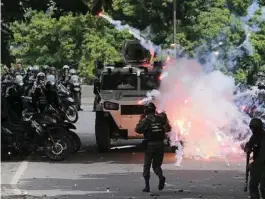  ?? Fernando Llano / Associated Press ?? Fireworks launched by anti-government protesters explode near Bolivarian national guard officers as security forces work to keep protesters from marching to the Supreme Court in Caracas.