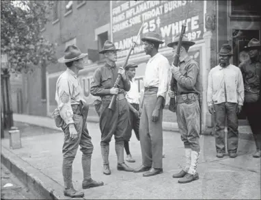  ?? CHICAGO HISTORY MUSEUM — THE JUN FUJITA NEGATIVES COLLECTION VIA AP ?? In this 1919photo provided by the Chicago History Museum, armed National Guard and African American men stand on a sidewalk during race riots in Chicago. It was 100years ago, in the “Red Summer” of race riots that spread across the United States, but the terror of those days still reverberat­es in a city that continues to grapple with segregatio­n, housing discrimina­tion, and deep tension between residents and police.