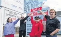  ?? KIRK STARRATT ?? The Flower Cart Group bakery workers Jenn McCarol and Devin MacLeod, of Wolfville, and Amy Phinney, of Greenwood, and CEO Jeff Kelly with the sold sign outside of the organizati­on’s 9412 Commercial St. building in New Minas.