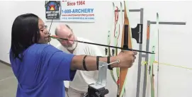  ?? PAUL A. SMITH ?? Lyle Maryniak of Wauwatosa watches as Katrina Rainey of Milwaukee, who is blind, prepares to take a shot at West Town Archery in Brookfield.