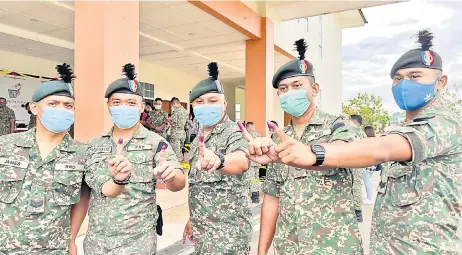  ?? — Photo by Roystein Emmor ?? Army personnel show their fingers marked with indelible ink a er casting their votes at the Muara Tuang camp.