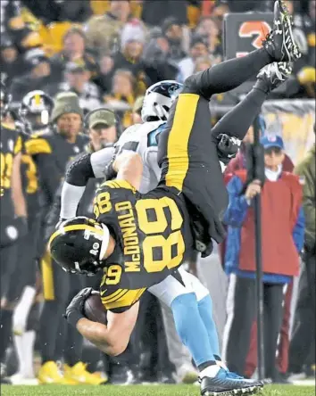  ?? Matt Freed/Post-Gazette ?? Vance McDonald is upended by Panthers safety Eric Reid in the third quarter Thursday night at Heinz Field. McDonald finished with four catches for 44 yards.