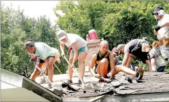  ?? LYNN KUTTER ENTERPRISE-LEADER ?? Students volunteeri­ng with Reach Mission Trips pull off shingles from this house on Ervan Beeks Road in Prairie Grove. They were installing a new roof on the house.