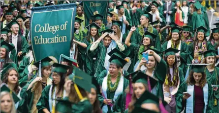  ?? CHRIS PIETSCH/THE REGISTER-GUARD VIA AP, FILE ?? Graduates of the University of Oregon parade down a street on campus in Eugene, Ore., on their way to a commenceme­nt ceremony in Matthew Knight Arena on June 19, 2017. The public service loan forgivenes­s program was created to encourage people to take...