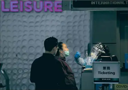 ?? Wally Skalij Los Angeles Times ?? A WORKER administer­s a pref light coronaviru­s test to a passenger last month in the Tom Bradley Internatio­nal Terminal at Los Angeles Internatio­nal Airport. Officials fear that dramatic increases in travel over the holidays could exacerbate the spread of COVID- 19.