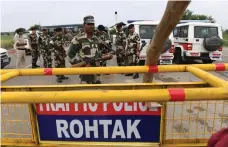  ?? AP; AFP ?? Supporters of the Dera Sacha Sauda sect attack a member of the media in Panchkula, India, last week. Security personnel stand guard along a road near Sonariya jail where the controvers­ial guru is housed