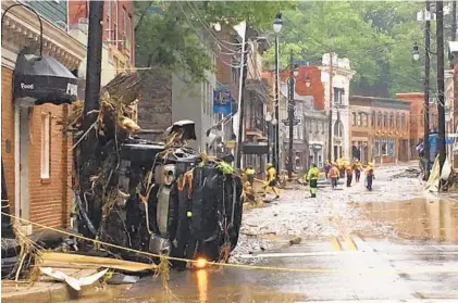  ?? LIBBY SOLOMON/BALTIMORE SUN MEDIA GROUP ?? Rescue personnel walk along Ellicott City’s Main Street on Sunday after a flood ravaged the historic district. Howard County Executive Allan H. Kittleman said Sunday that “this is worse” than the storm of July 2016 which killed two people and destroyed...