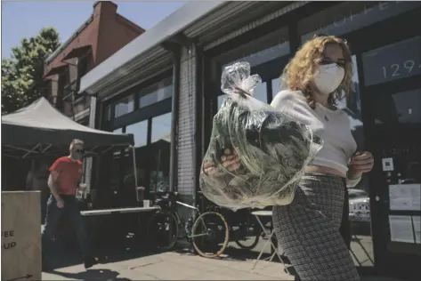  ?? FASHION DESIGNER JOSIE VAND WEARS DAMIAN DOVARGANES ?? a facemask as she retrieves a bag with organic vegetables from a farm box from County Line Harvest in Los Angeles on Friday.