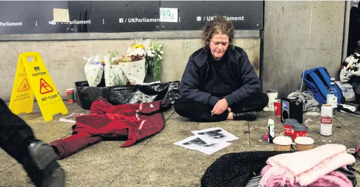  ??  ?? Above, Dawn Hodgson, a 45-year-old homeless woman from Newcastle, sits beside a shrine for her homeless friend Gyula Remes meters from the entrance to the Houses of Parliament in Westminste­r Undergroun­d Station.The homeless man, known as Gyula Remes, was found collapsed at Westminste­r Undergroun­d station opposite the Houses of Parliament on the night of December 18. He died in hospital the following day. Today the Office of National Statistics releases figures estimating that 597 homeless people died in England and Wales in 2017, an increase of 24% over five years. Below, Dawn writes a message on a photograph of her homeless friend Gyula Remes