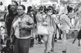  ?? MATT ROURKE/AP ?? Customers, including some in face masks, shop at Philadelph­ia’s Reading Terminal Market on Friday. A renewed indoor mask mandate in the city lasted only a few days.